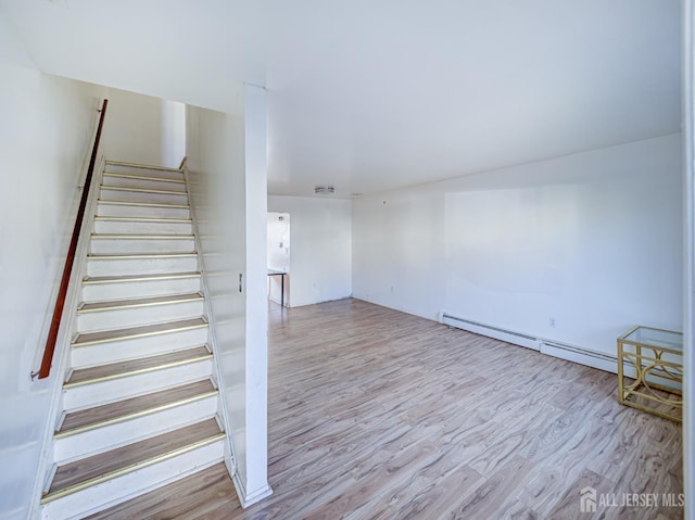 staircase featuring a baseboard heating unit and wood finished floors