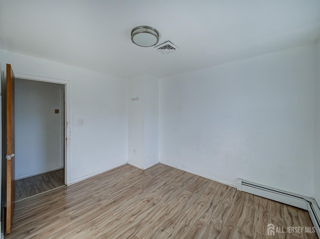 empty room with a baseboard heating unit, visible vents, and light wood-style floors