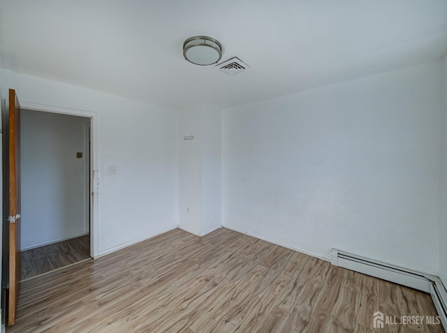 unfurnished room featuring baseboard heating, light wood-style flooring, and visible vents