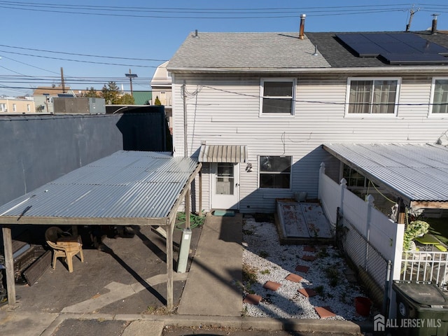 rear view of property with roof with shingles and fence
