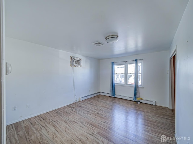 empty room with a baseboard heating unit, visible vents, light wood-style flooring, and a wall mounted air conditioner