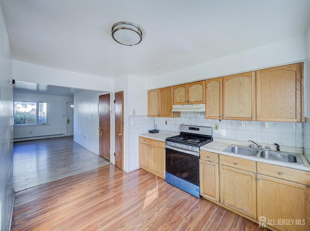 kitchen with gas stove, light countertops, a sink, under cabinet range hood, and light wood-style flooring