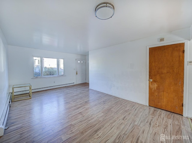 unfurnished room with light wood finished floors and a baseboard radiator