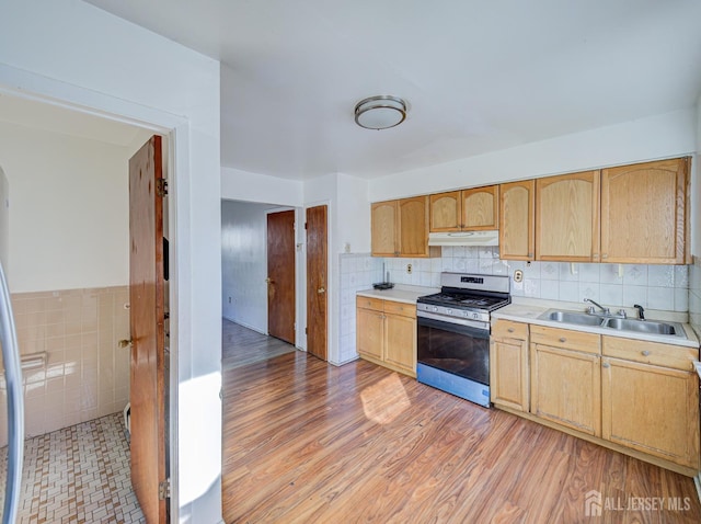 kitchen with light brown cabinetry, stainless steel gas range oven, light countertops, under cabinet range hood, and a sink