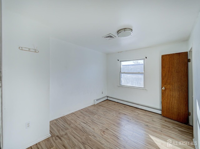 spare room featuring a baseboard heating unit, visible vents, and light wood-style flooring