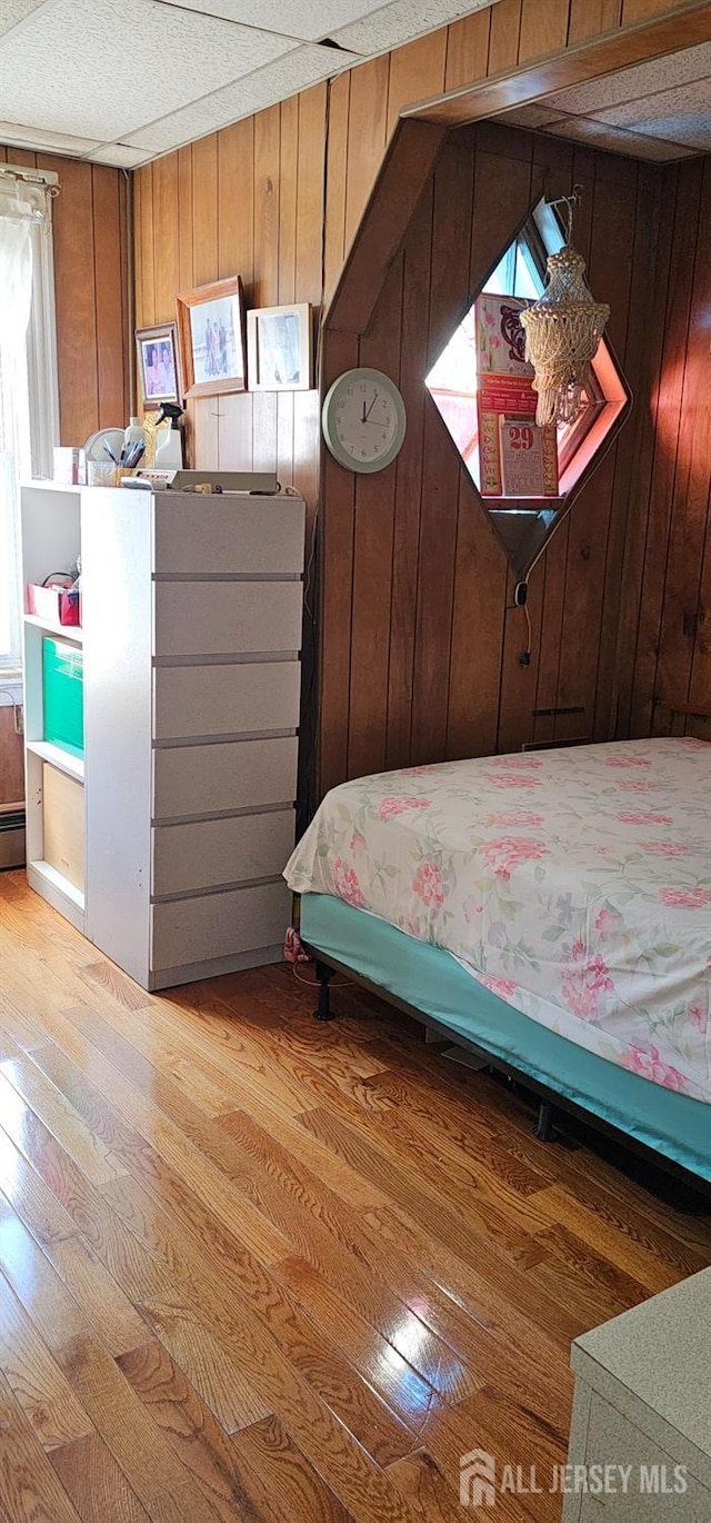 unfurnished bedroom with wood walls, hardwood / wood-style floors, and a baseboard radiator