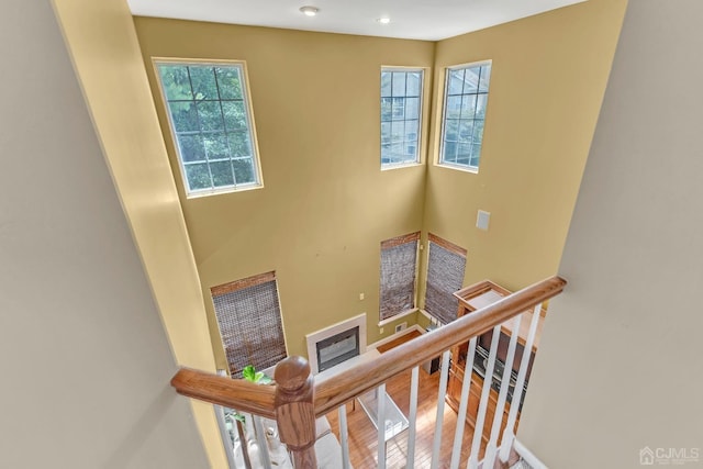 stairway featuring baseboards, wood finished floors, and a glass covered fireplace