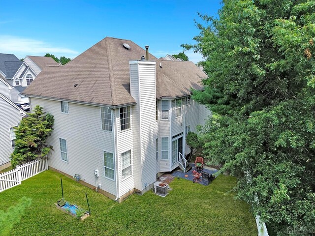 rear view of property featuring a yard and central AC unit