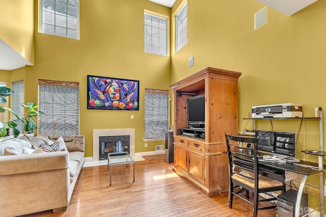 living room featuring light wood-style flooring, a fireplace with flush hearth, and a wealth of natural light