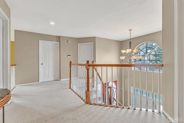 hall featuring an inviting chandelier and light carpet