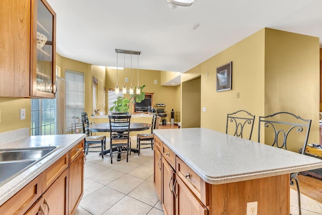 kitchen with light countertops, brown cabinets, glass insert cabinets, and a kitchen breakfast bar