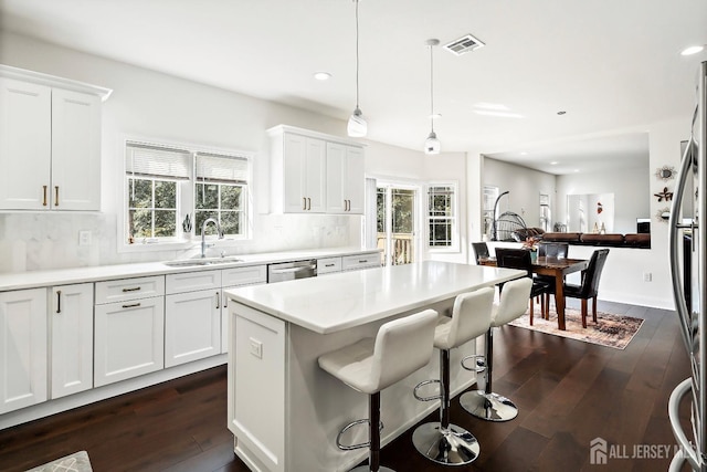 kitchen with appliances with stainless steel finishes, tasteful backsplash, sink, white cabinets, and hanging light fixtures