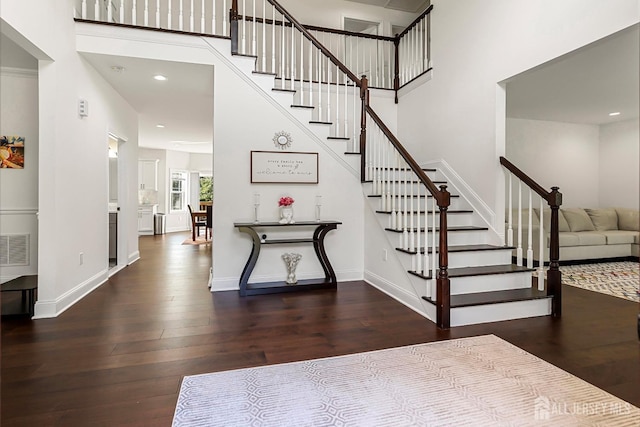 staircase with a towering ceiling and hardwood / wood-style floors