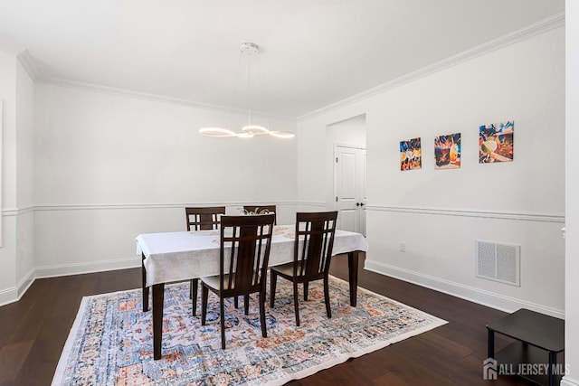 dining area with ornamental molding, dark wood-type flooring, and a notable chandelier