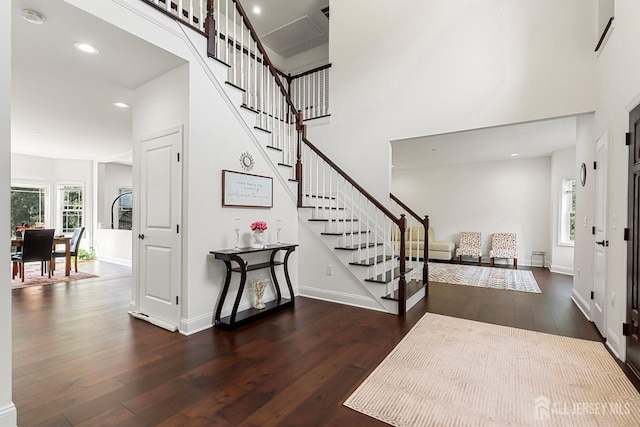 entryway featuring dark wood-type flooring, a healthy amount of sunlight, and a high ceiling