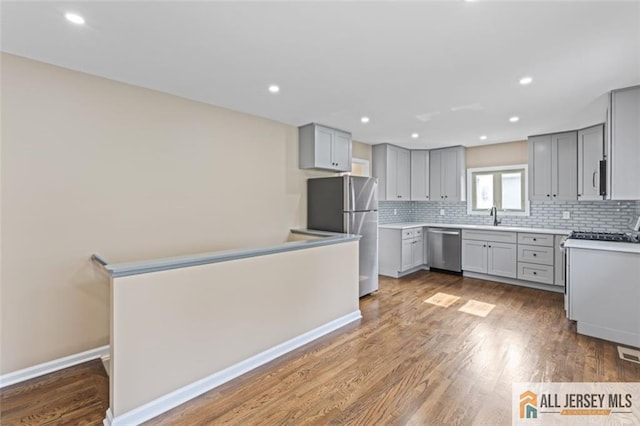 114 Holly St, Port Reading, NJ 07064 - kitchen featuring stainless steel appliances, gray cabinetry, backsplash, wood finished floors, and recessed lighting