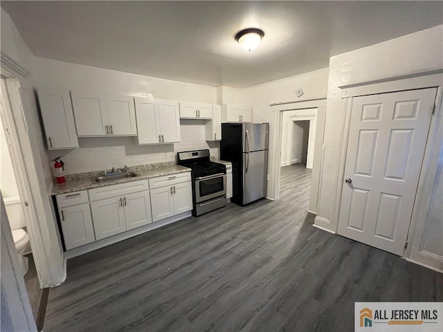 427 John St, Plainfield, NJ 07060 - kitchen with appliances with stainless steel finishes, dark wood-style floors, a sink, light stone counters, and backsplash