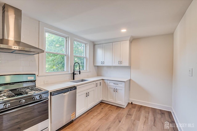 160 Academy St, South Orange Village, NJ 07079 - kitchen featuring appliances with stainless steel finishes, wall chimney exhaust hood, light countertops, light wood-type flooring, and white cabinetry