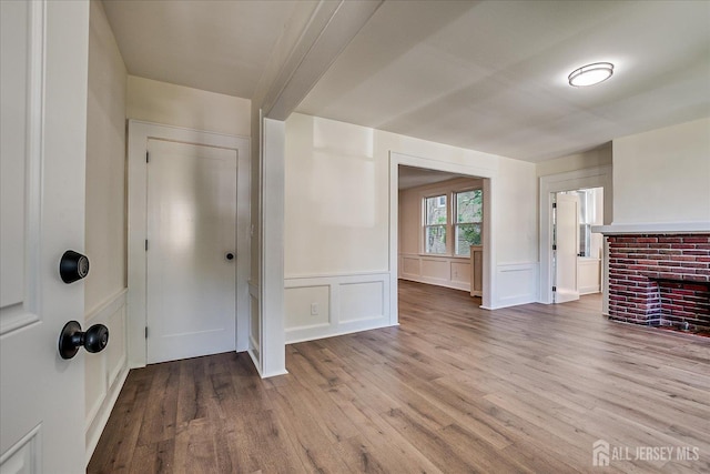 160 Academy St, South Orange Village, NJ 07079 - unfurnished living room featuring wood finished floors, a brick fireplace, wainscoting, and a decorative wall