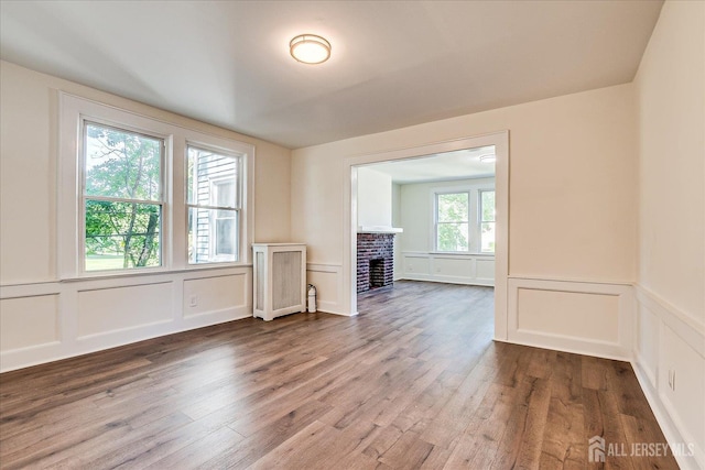 160 Academy St, South Orange Village, NJ 07079 - unfurnished room featuring a decorative wall, wood finished floors, a brick fireplace, and a wainscoted wall