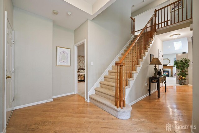 27 Dawson Ln, Monroe, NJ 08831 - entryway with stairway, a glass covered fireplace, light wood finished floors, baseboards, and a high ceiling