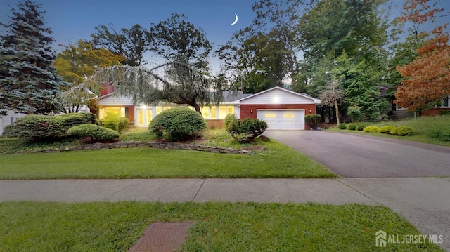 single story home with an attached garage, aphalt driveway, a front lawn, and brick siding