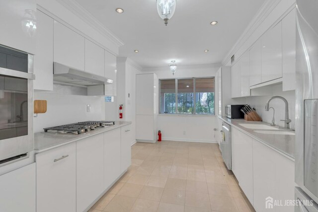 kitchen featuring under cabinet range hood, stainless steel gas cooktop, a sink, and white cabinetry