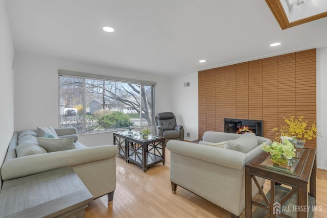 living room featuring a fireplace, recessed lighting, visible vents, and light wood-type flooring