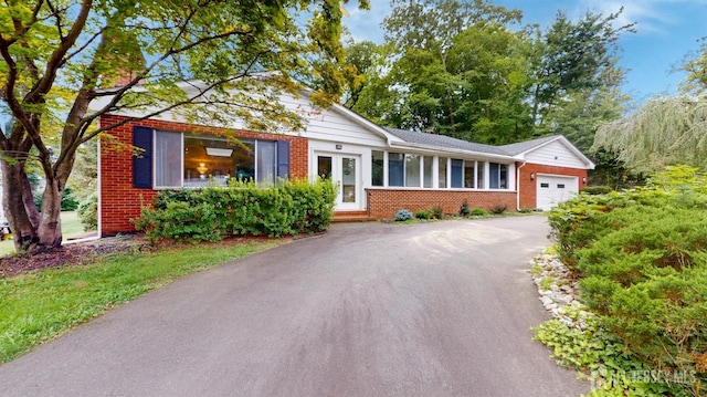 view of front of property featuring a garage, brick siding, and driveway