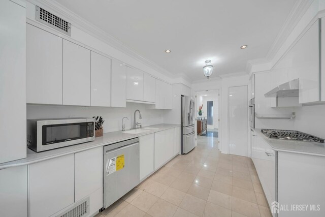 kitchen with range hood, visible vents, white cabinets, a sink, and stainless steel appliances