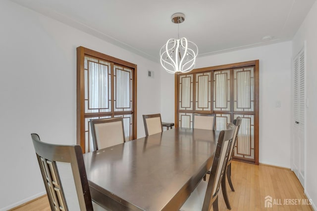 dining room with a chandelier, visible vents, and light wood-type flooring