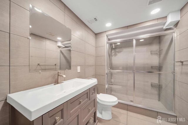 bathroom with toilet, visible vents, tile walls, and a stall shower