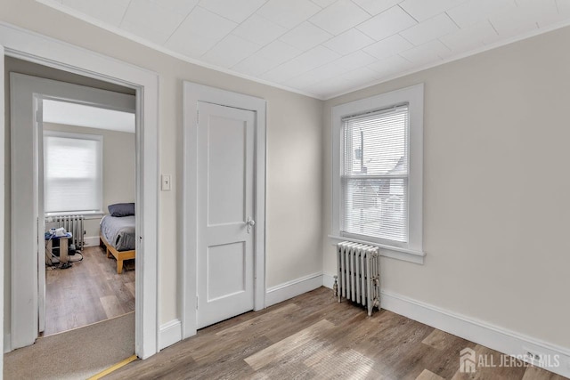 bedroom with radiator, crown molding, and wood finished floors