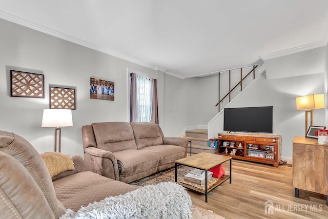 living room featuring wood finished floors, stairs, and crown molding