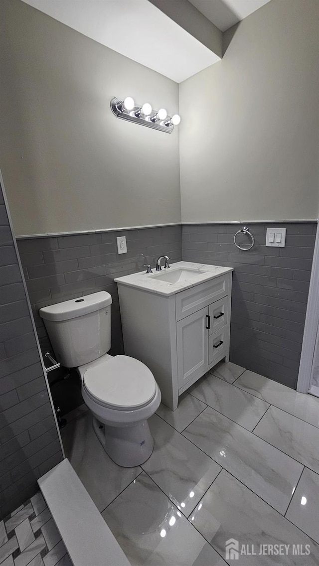 1150 Rahway Ave, Avenel, NJ 07001 - half bathroom featuring tile walls, toilet, wainscoting, vanity, and marble finish floors