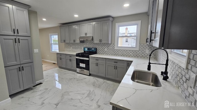 1150 Rahway Ave, Avenel, NJ 07001 - kitchen with stainless steel gas range oven, gray cabinets, under cabinet range hood, a sink, and baseboards