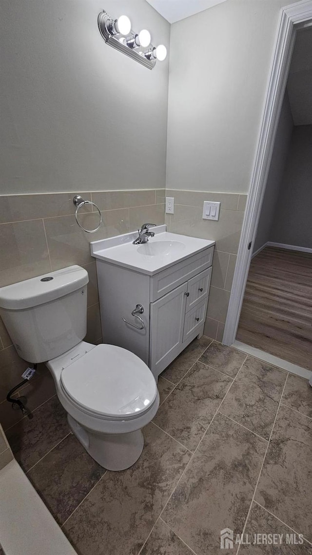1150 Rahway Ave, Avenel, NJ 07001 - half bath with tile walls, vanity, toilet, tile patterned flooring, and a wainscoted wall