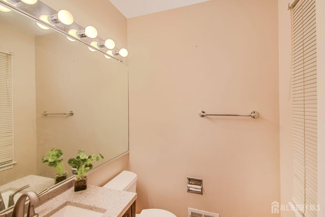 bathroom with toilet, visible vents, a closet, and vanity