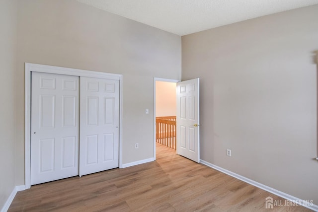 unfurnished bedroom featuring a closet, baseboards, and light wood finished floors