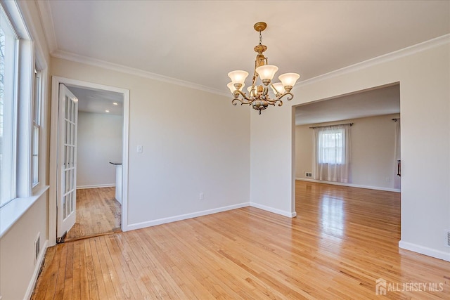 spare room with a notable chandelier, light wood-style flooring, baseboards, visible vents, and crown molding