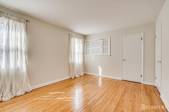 unfurnished room with light wood-style flooring and baseboards