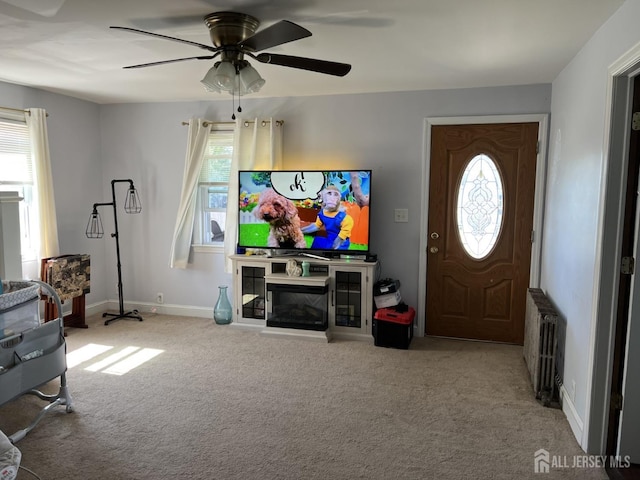 living room with ceiling fan, a healthy amount of sunlight, light colored carpet, and radiator heating unit