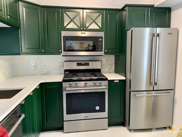 kitchen with decorative backsplash, marble finish floor, appliances with stainless steel finishes, and green cabinets