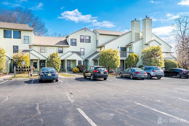 view of front of house featuring a residential view, a chimney, and uncovered parking