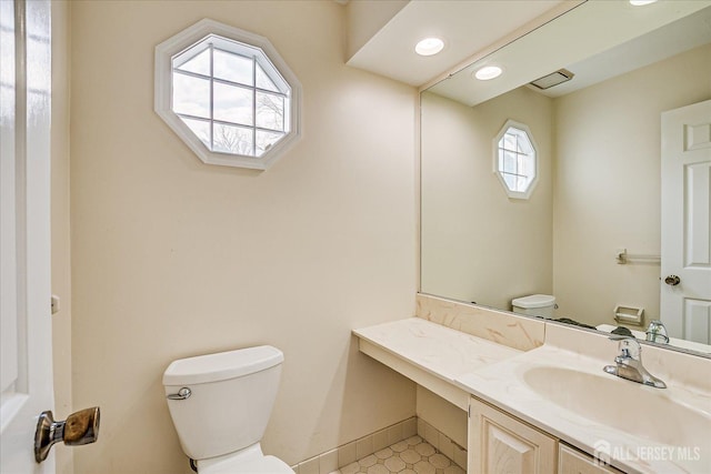 bathroom featuring toilet, visible vents, baseboards, and vanity