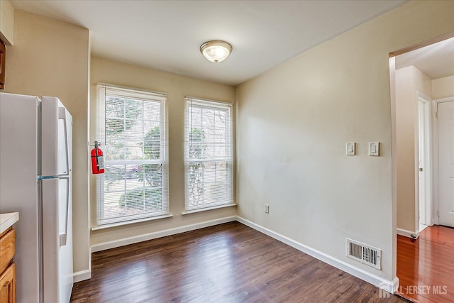 kitchen with wood finished floors, visible vents, baseboards, light countertops, and freestanding refrigerator