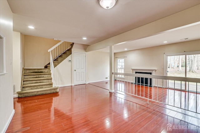 spare room with a fireplace, wood finished floors, and a healthy amount of sunlight