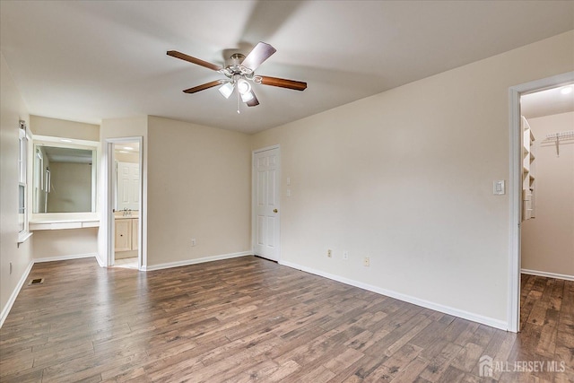 unfurnished bedroom featuring visible vents, baseboards, wood finished floors, a walk in closet, and a closet