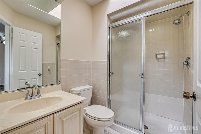 bathroom with toilet, a stall shower, tile walls, and vanity