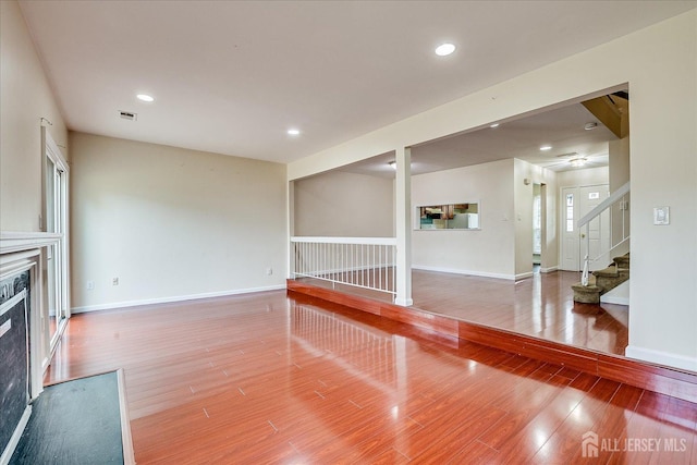 unfurnished living room featuring recessed lighting, a fireplace, light wood-style flooring, and stairs